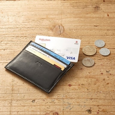 テーブルに置かれたクレジットカードが入ったエイジのカードケース Plus と４枚のコイン