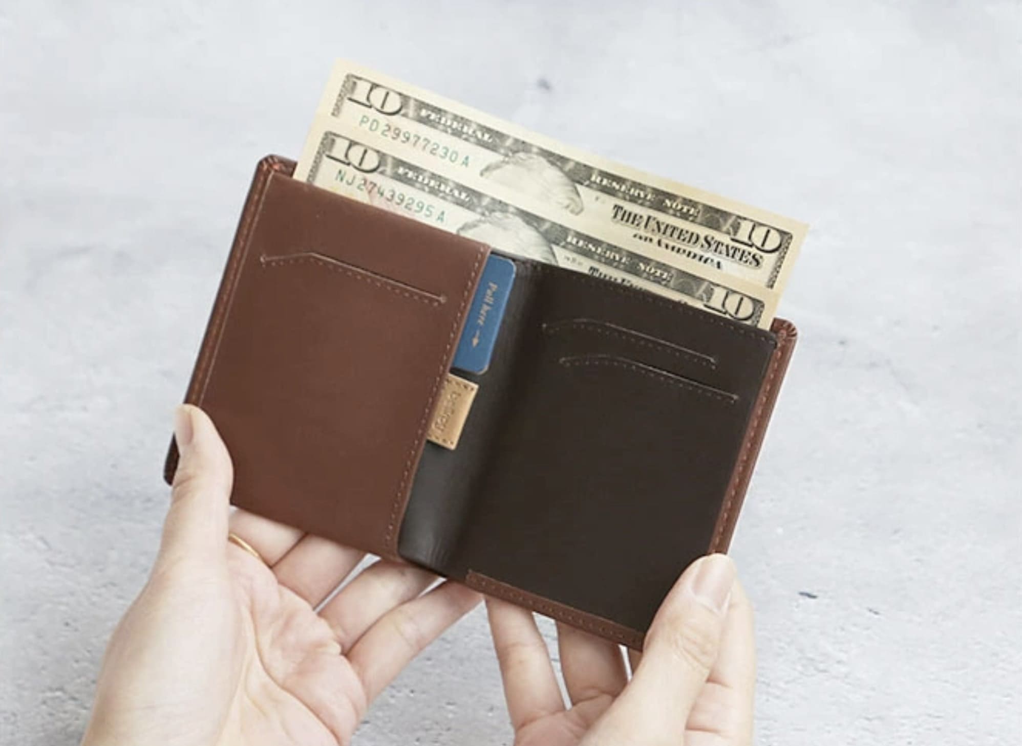 開いたブラウンの二つ折り財布から２枚お札が出ている状態