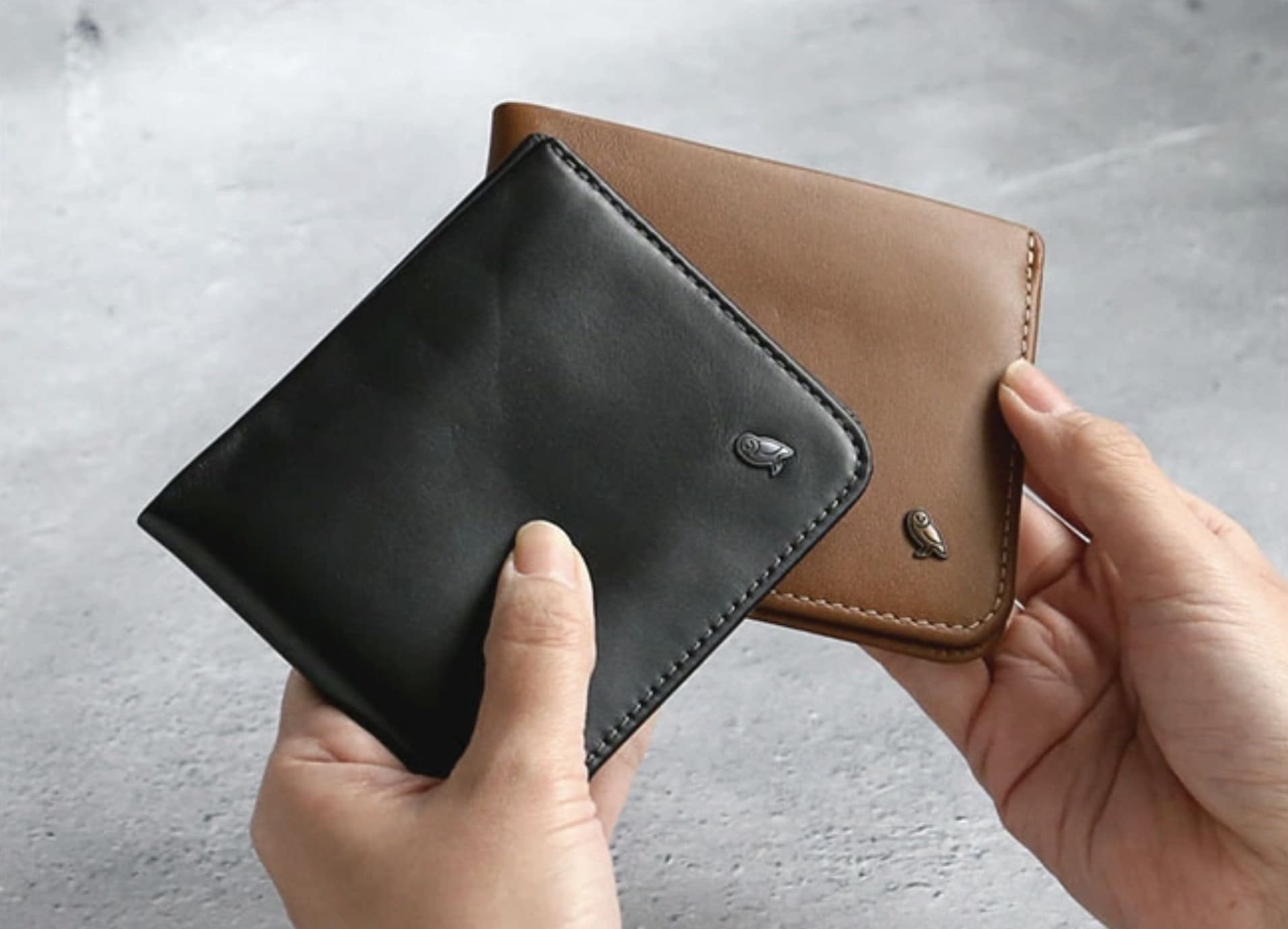 左手にベルロイの黒い二つ折り財布、右手にブラウンの二つ折り財布を持っている状態

