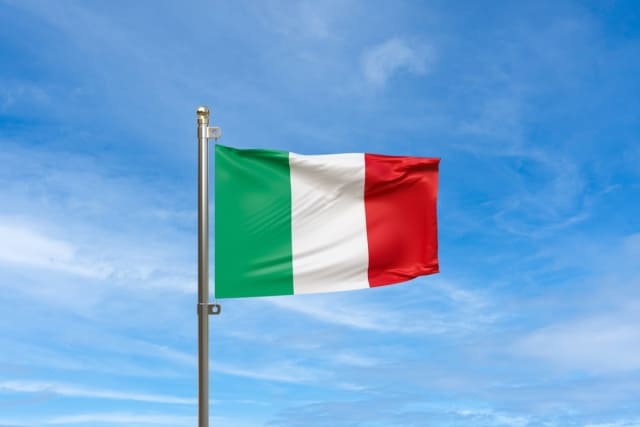 青空の下、イタリアの国旗である緑・白・赤の縦三色旗が風になびいている