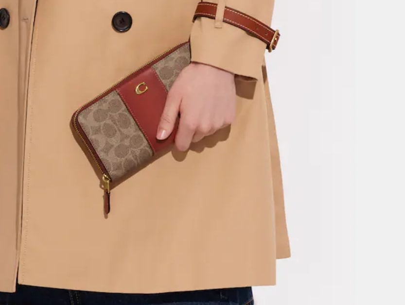 シグネチャーキャンバスの長財布を手に持つコートを着た女性