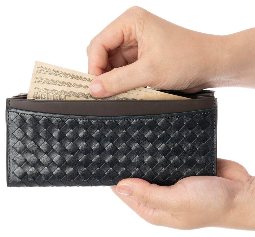 黒いマットーネレザーを編み込んだ長財布から紙幣を取り出している手