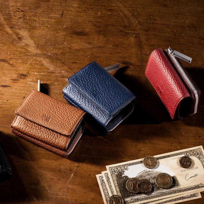 テーブルの上に置かれたブラウン、ネイビー、レッドの財布と紙幣とコイン