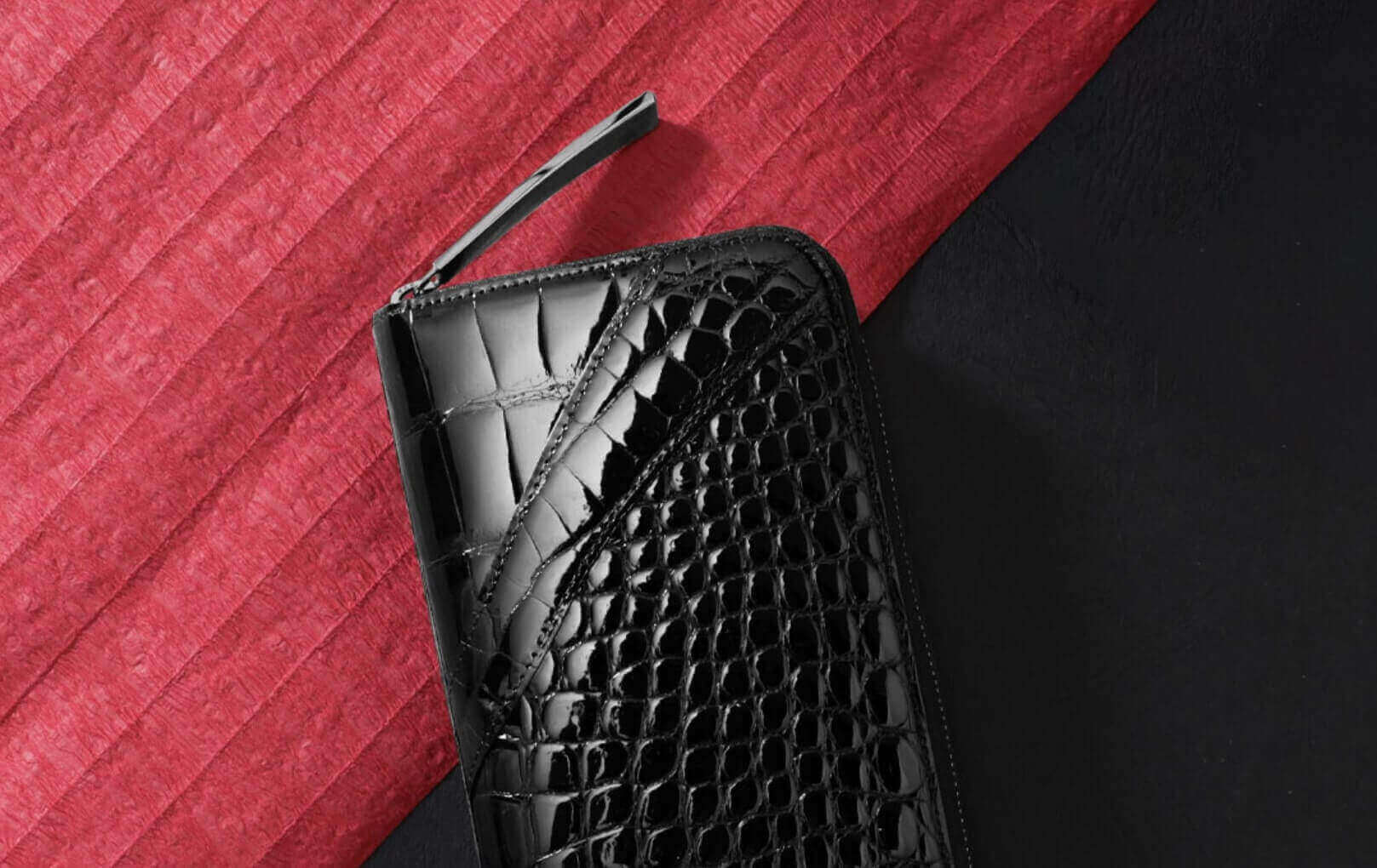 赤い布の上に置かれた池田工芸のクロコダイル財布ブラック