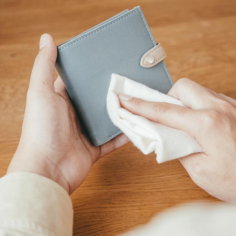 財布を布で拭いてメンテナンスする女性の手