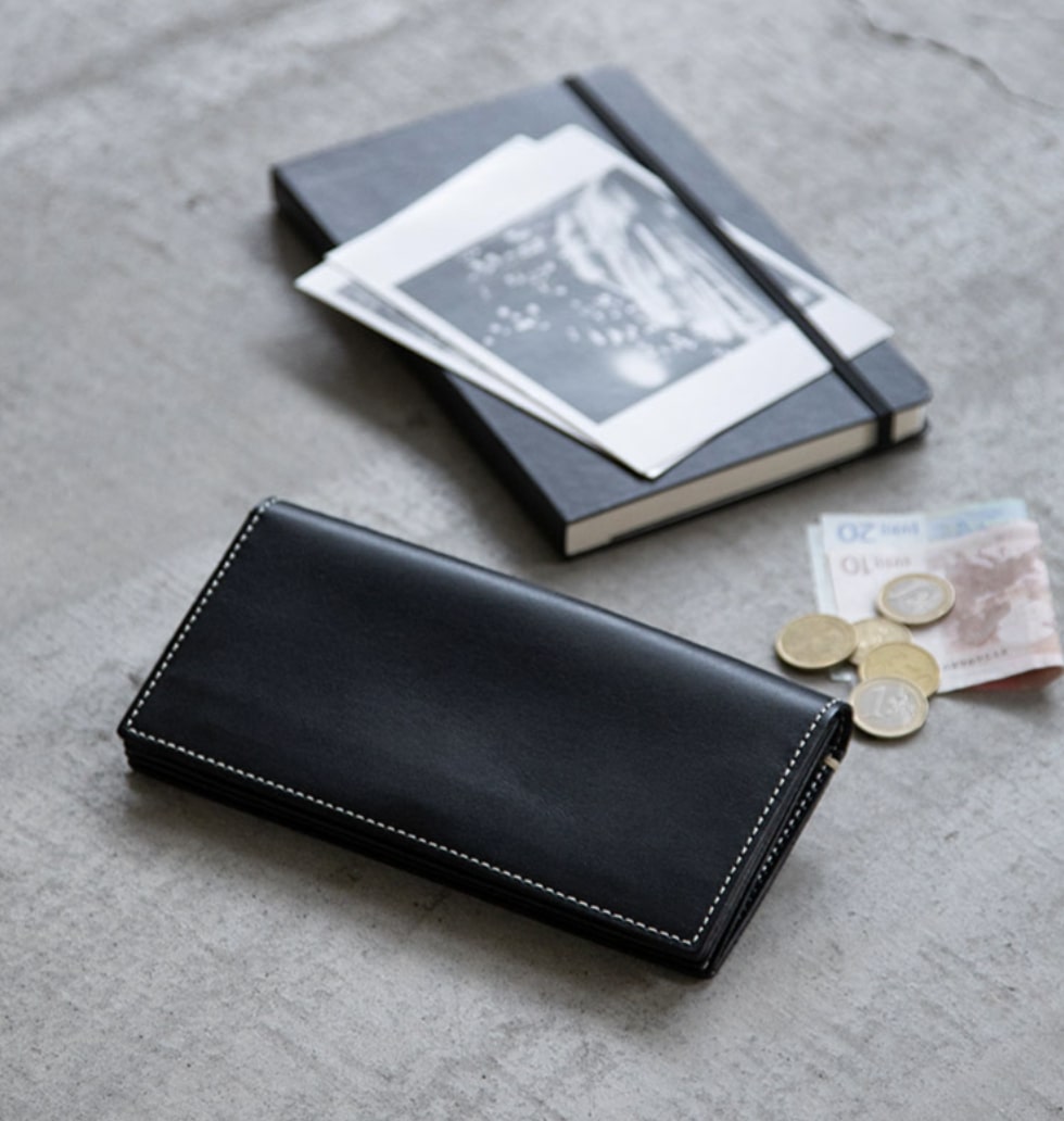 土屋鞄製作所 ブラックの二つ折り長財布と海外通貨と写真とノート