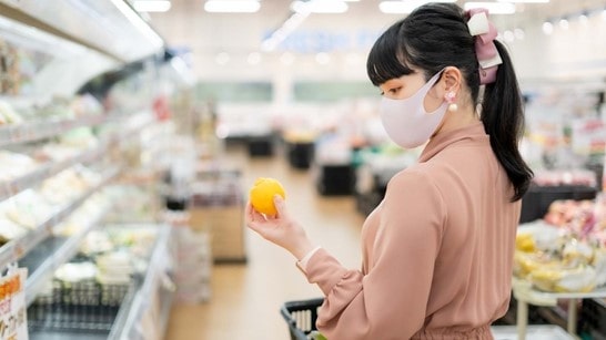 スーパーマーケットでレモンを持つ若い女性