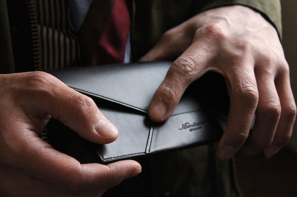 ブラックの封筒型長財布を持つ男性の手