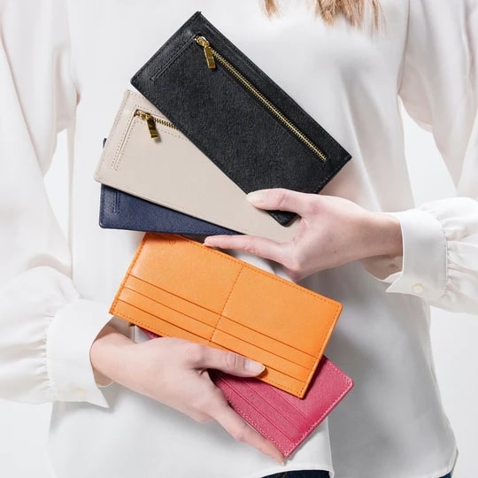 ムラの本革サフィアーノレザースキミング防止機能付き薄型長財布（5色）を持つ女性