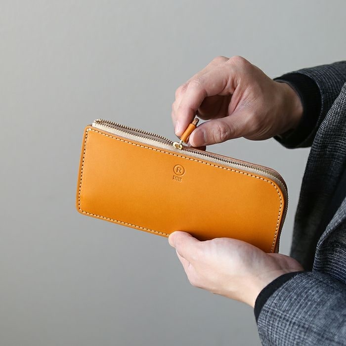 ポルコロッソの長財布のファスナーを開ける男性