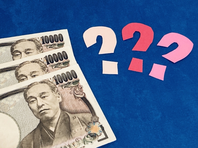 3枚の一万円札と紙で出来たハテナが3つ