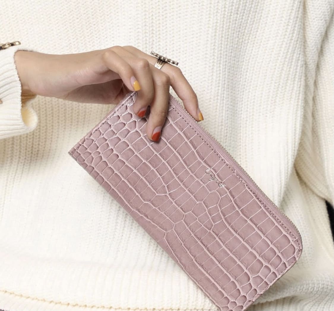 ピンクのシャイニースモールクロコ柄のL字ファスナー長財布を持つ女性
