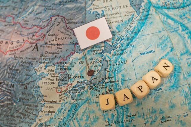 世界地図の日本に日本国旗のピンとJAPANと書かれた木製のビーズ