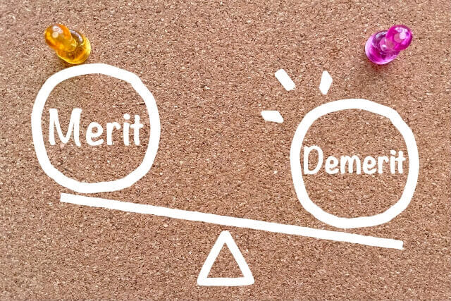 コルクボードに書かれたDemeritが乗ったはかりれたMeritとDemerit