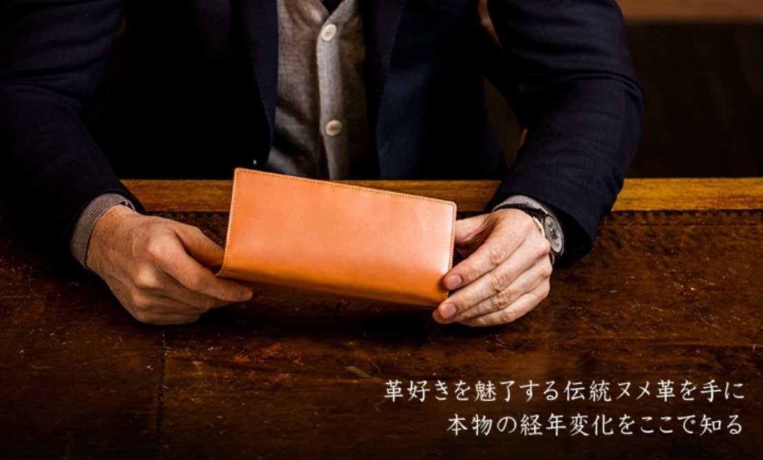 ココマイスターのパティーナ長財布を手に持つ男性